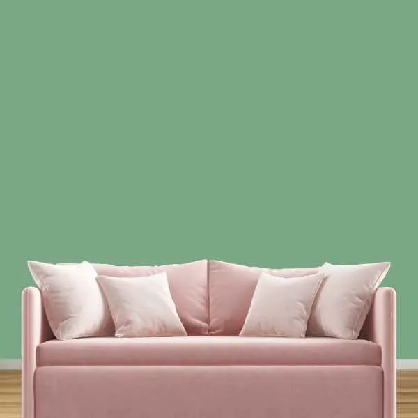 Blush pink couch in front of mint green wall.